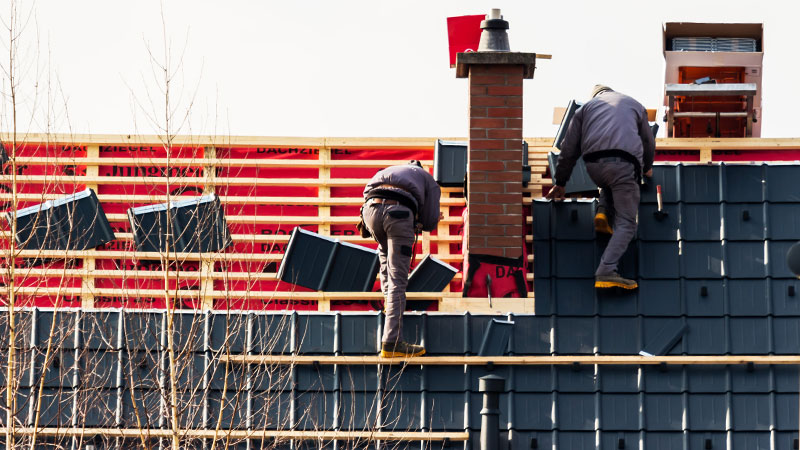 Ausbildung zum Dachdecker | Lehrling und Geselle auf dem Dach bei der Arbeit.